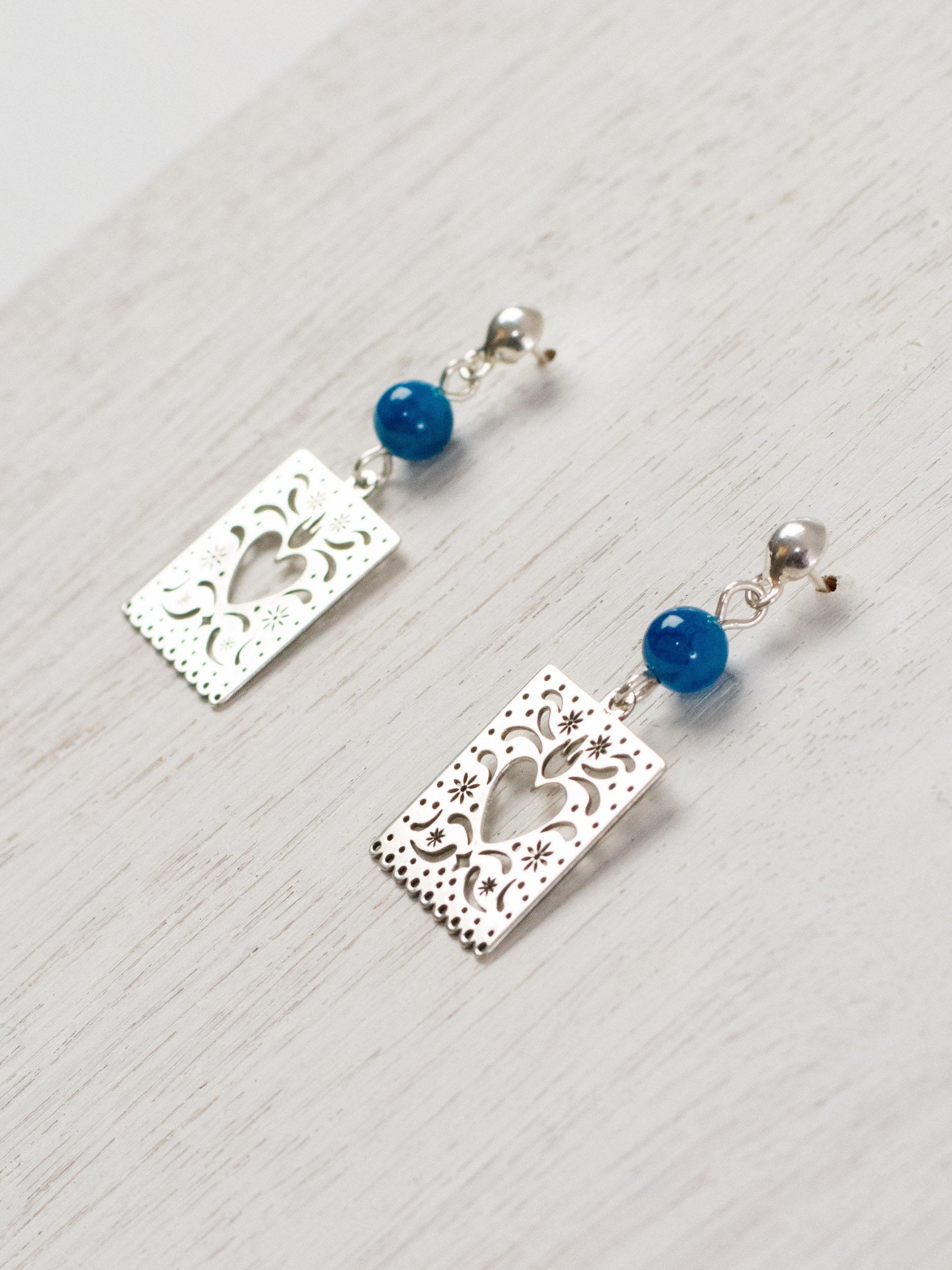 Cut-paper earrings with a heart and stones at the top