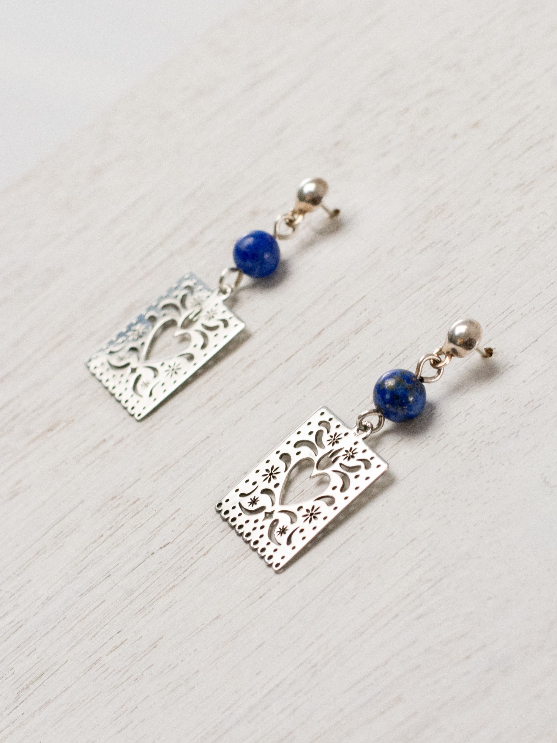 Cut-paper earrings with a heart and stones at the top